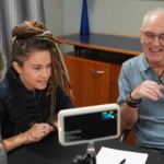 Heatherlyn and Steve Bassett are sat for a virtual interview. Camera equipment can be seen out of focus in the foreground.