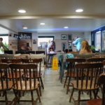 Heatherlyn, Matt and others set up for the gig at The Barn, with wooden chairs ready for the audience in the foreground.