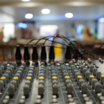 Dials on the sound desk with the room out of focus in the background.