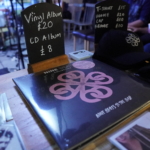 A Nine Beats Collective vinyl record in front of a sign that says: Vinyl Album £20, CD Album £8