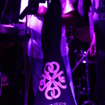 A Nine Beats Collective hoodie with a pink logo hangs from a microphone stand. Ben Okafor and Belinda Kae are partially in view.