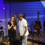 Ben Okafor and Heatherlyn stand together smiling on the stage area. Steve Bassett is partially in view in the background.